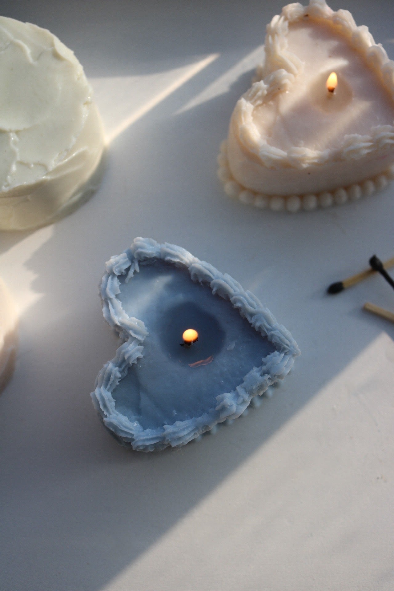 A decorative heart-shaped cake candle made from soy wax blend, showcasing its elegant design and soft color.