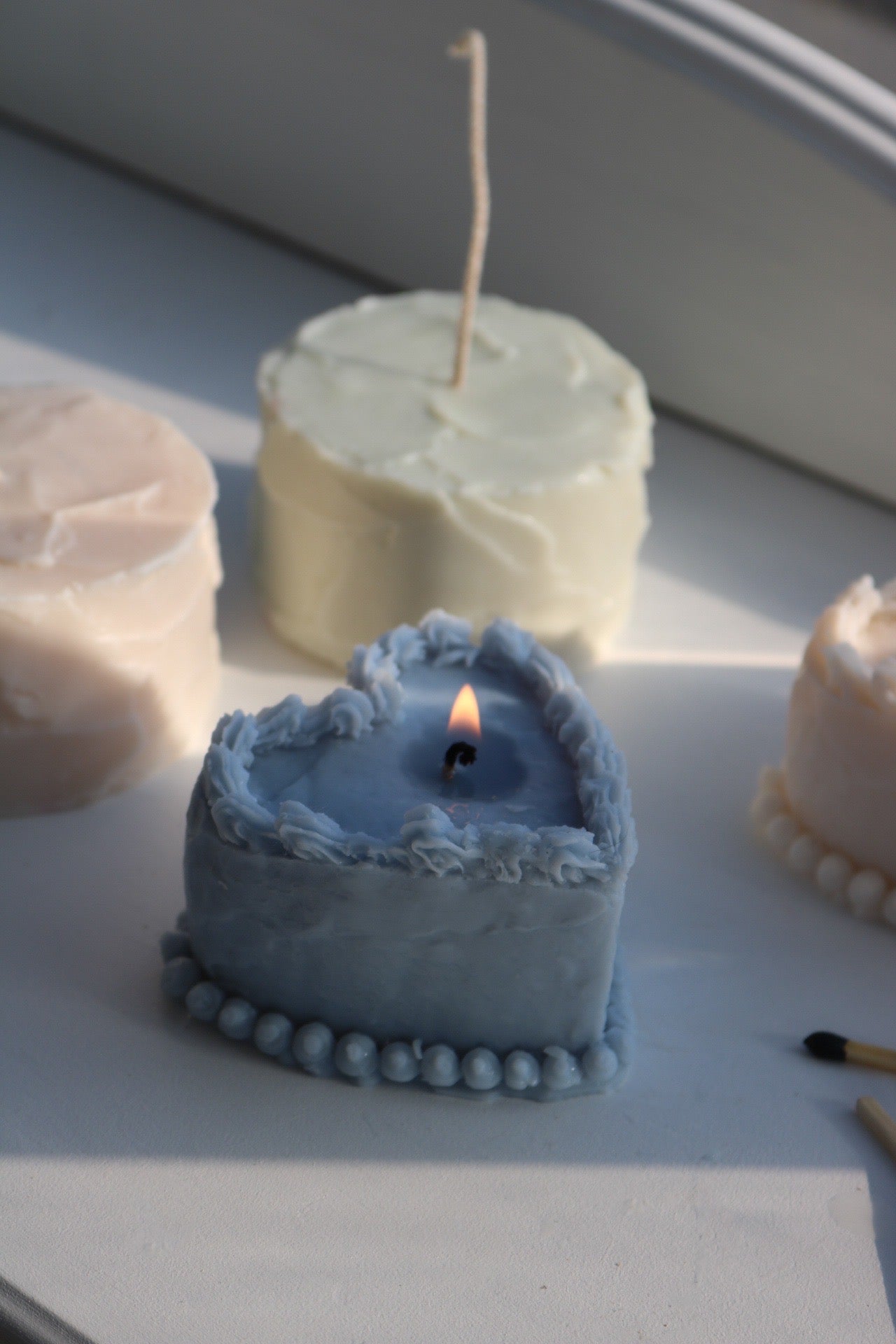 A decorative heart-shaped cake candle made from soy wax blend, showcasing its elegant design and soft color.