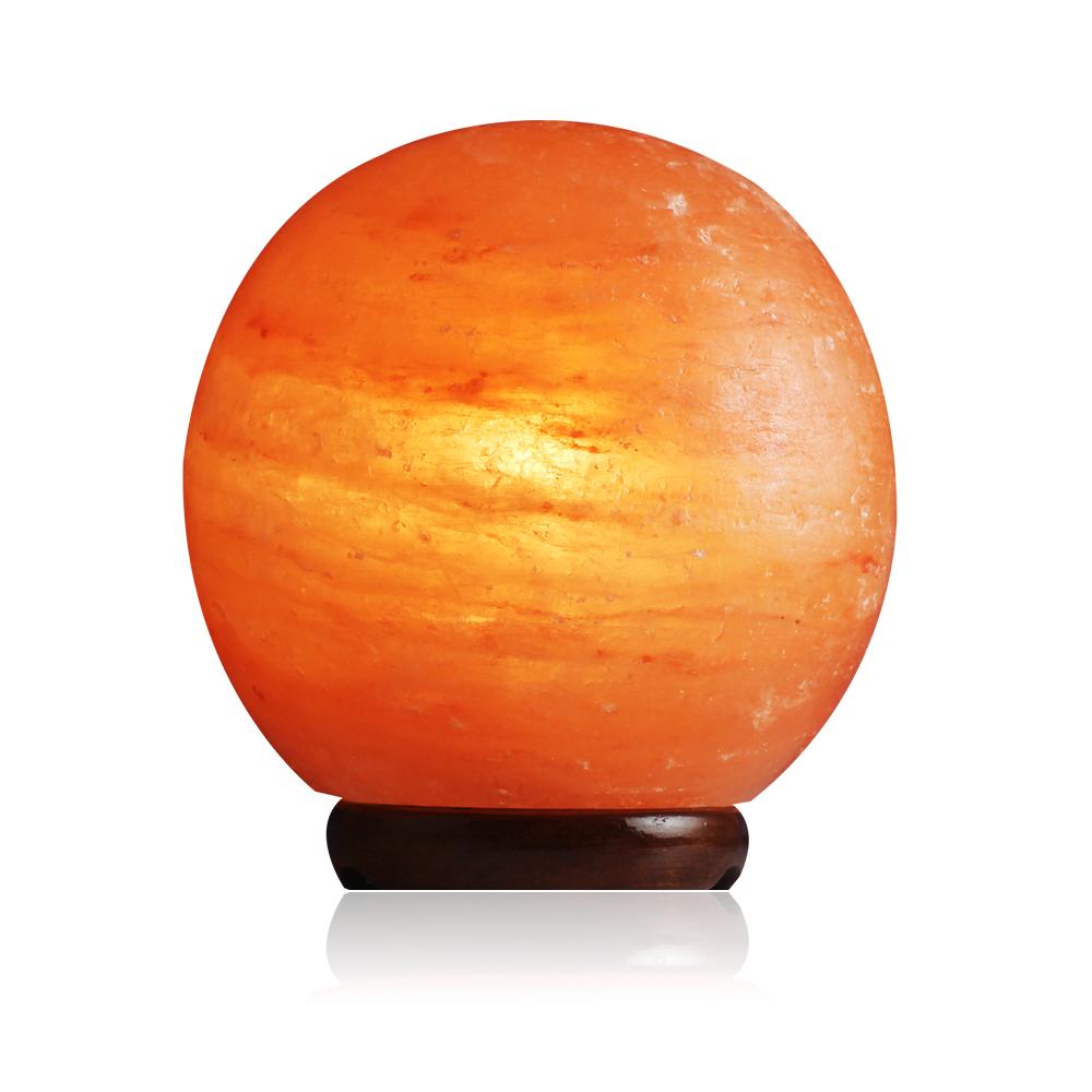 A beautifully crafted Himalayan Salt Lamp Globe made from natural salt crystals, emitting a warm amber glow, resting on a solid wooden base.