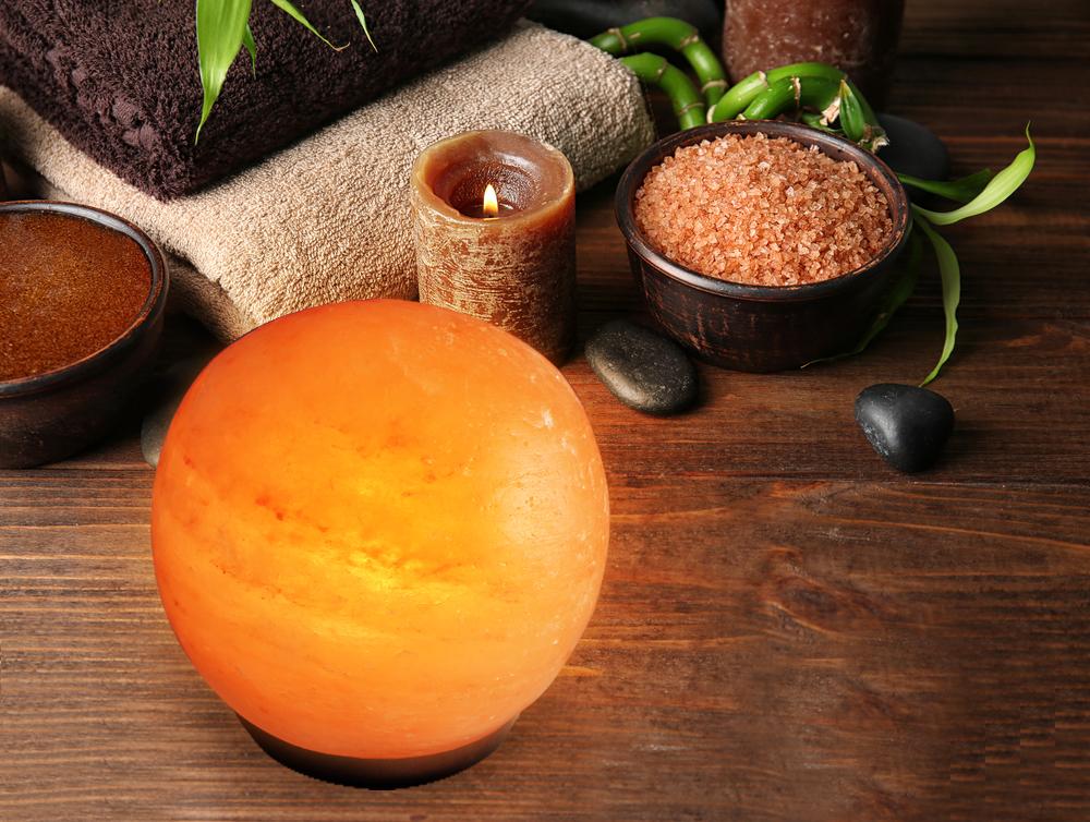 A beautifully crafted Himalayan Salt Lamp Globe made from natural salt crystals, emitting a warm amber glow, resting on a solid wooden base.