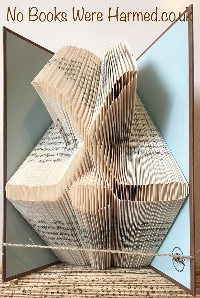 Artistic representation of hockey sticks and puck made from hand-folded vintage book pages, showcasing unique colors and designs.