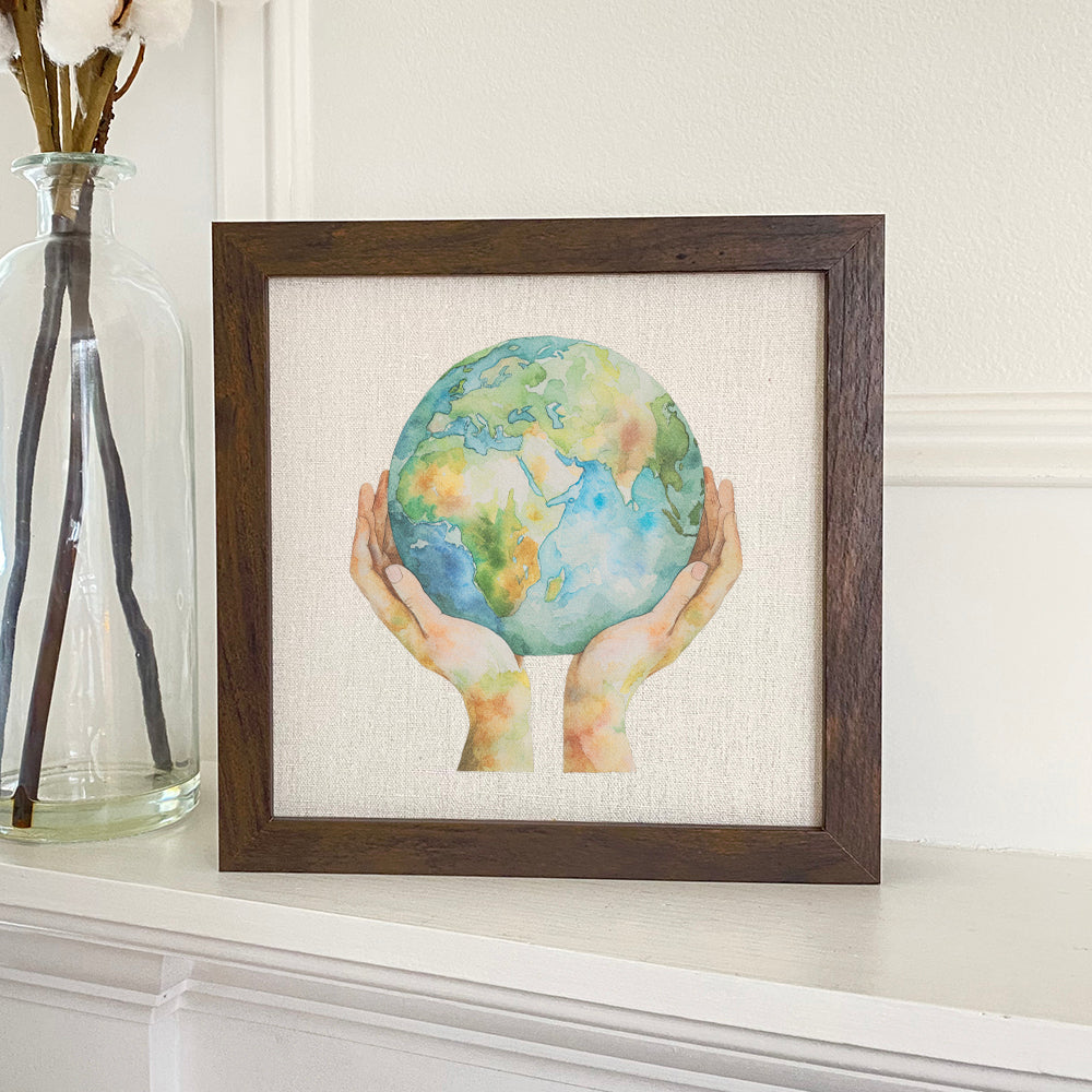 A beautifully crafted 'Holding the World' framed sign with a stylized wood frame, available in walnut or white-washed finish, featuring eco-friendly ink printing.