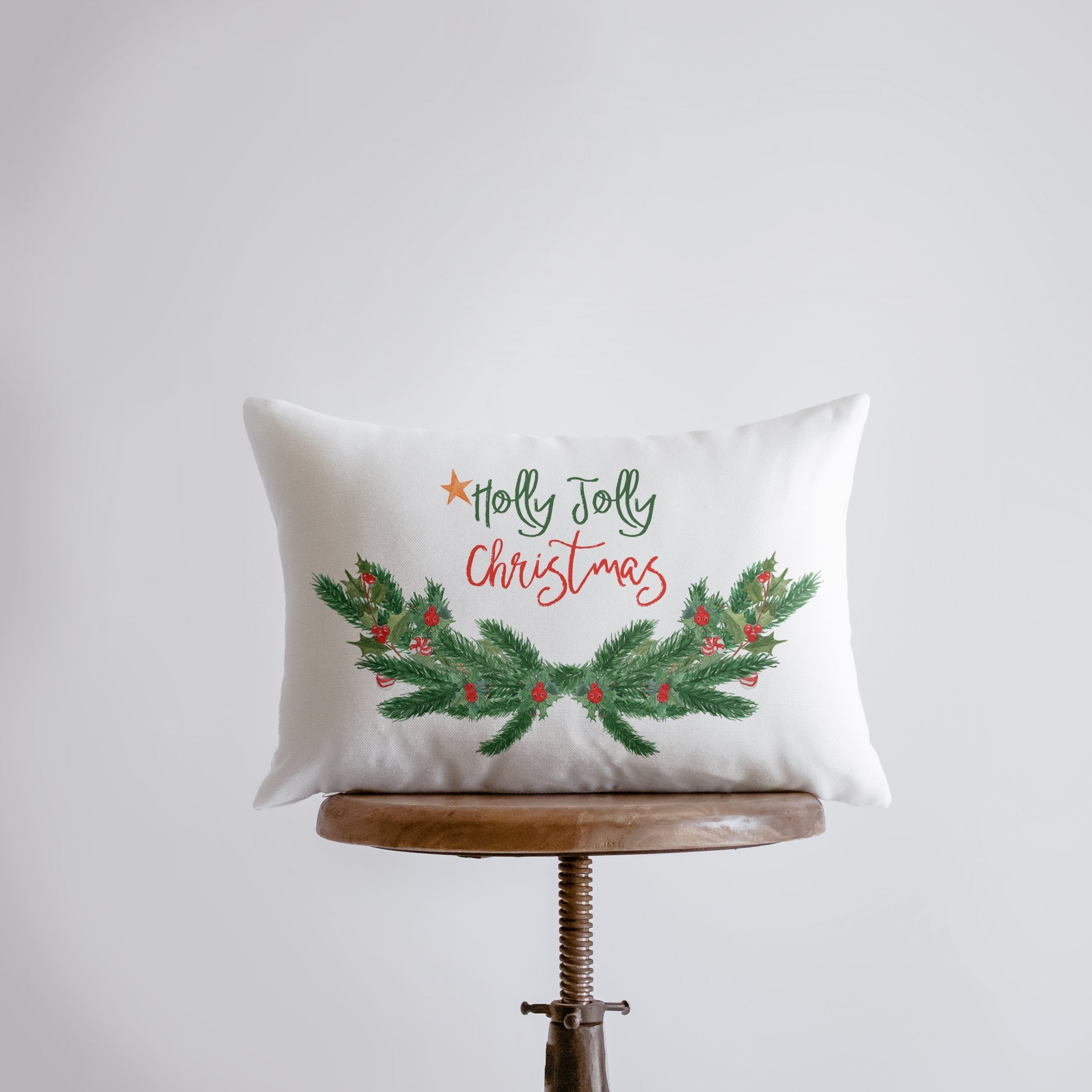 Holly Jolly Christmas Garland Pillow Cover with white background and pine tree swag design, measuring 18x12 inches.