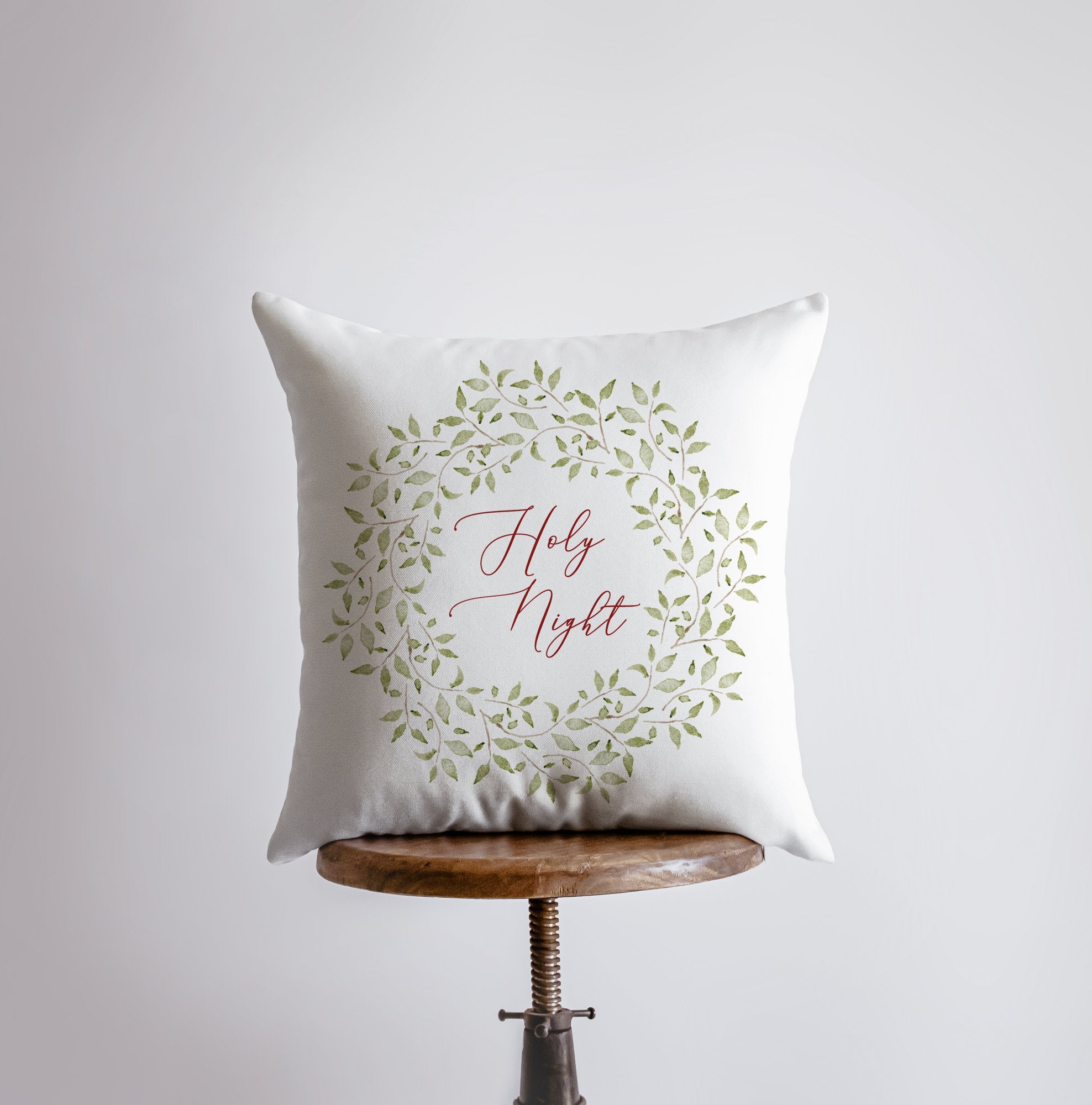 Holy Night Leaf Wreath Throw Pillow featuring red cursive text and eucalyptus wreath design on a white background.