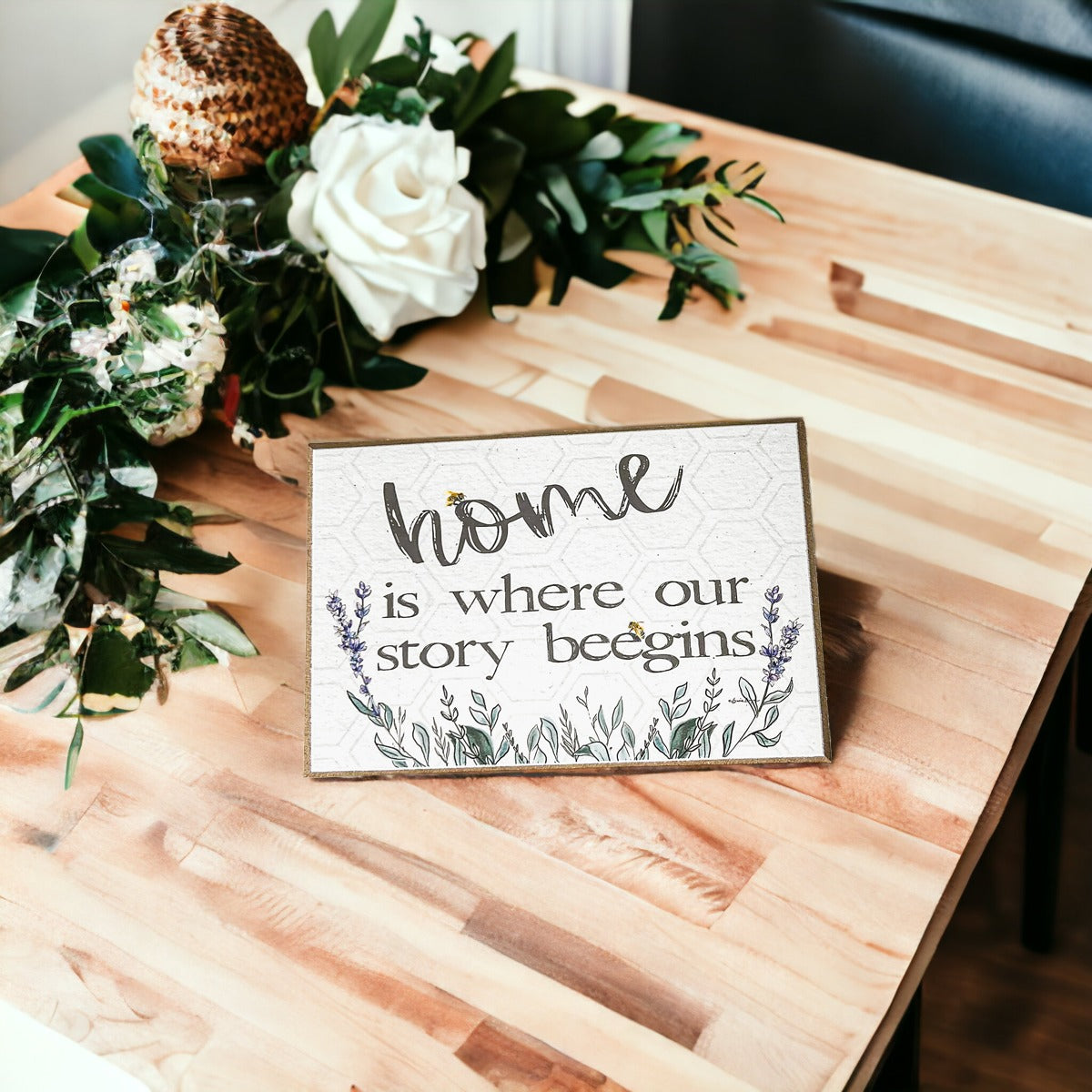 A decorative wooden block sign that reads 'HOME IS WHERE OUR STORY BEEGINS', featuring a rustic design suitable for various home decor styles.