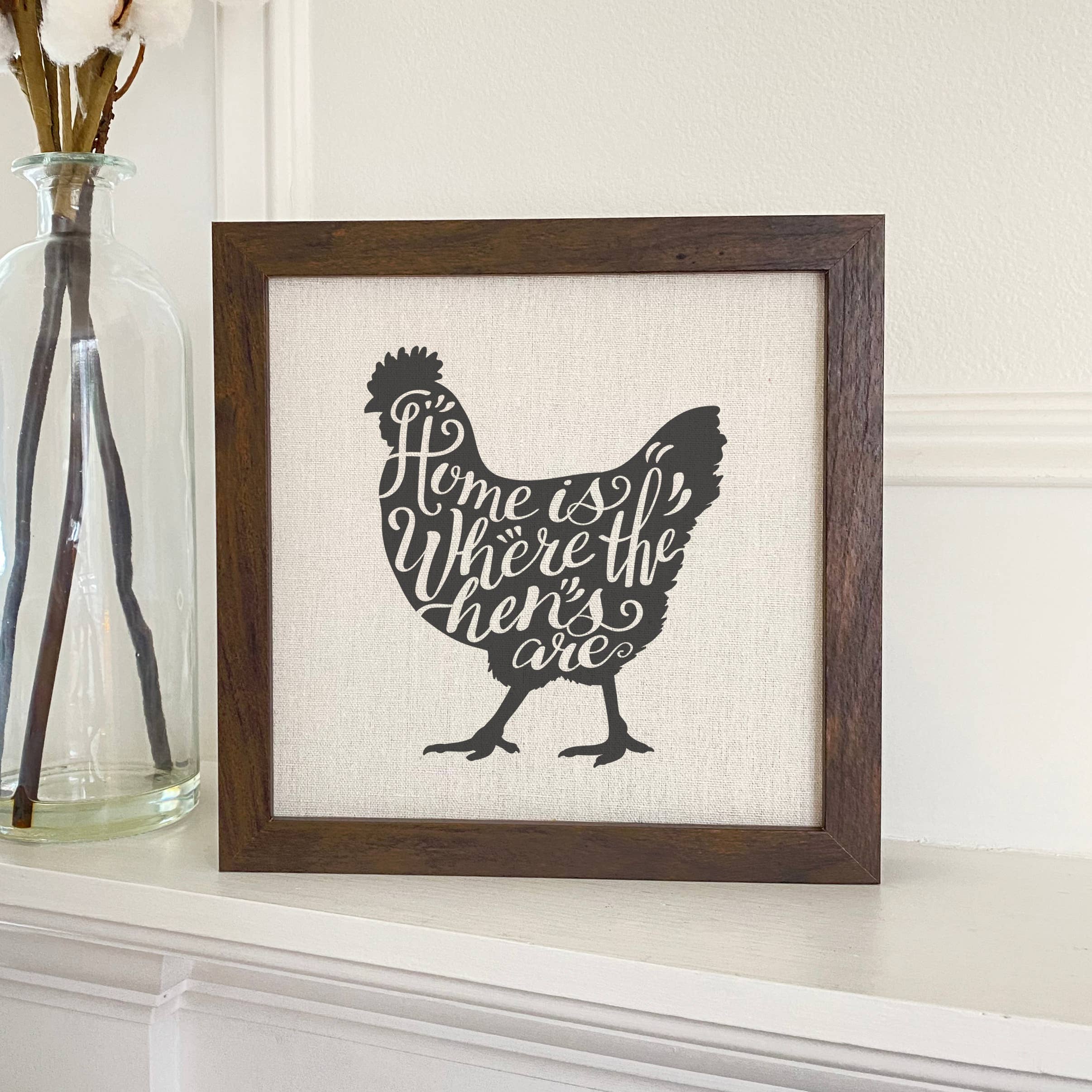 A charming 'Home is Chicken' framed sign with a stylized wood frame, featuring eco-friendly printing on a linen-look background.