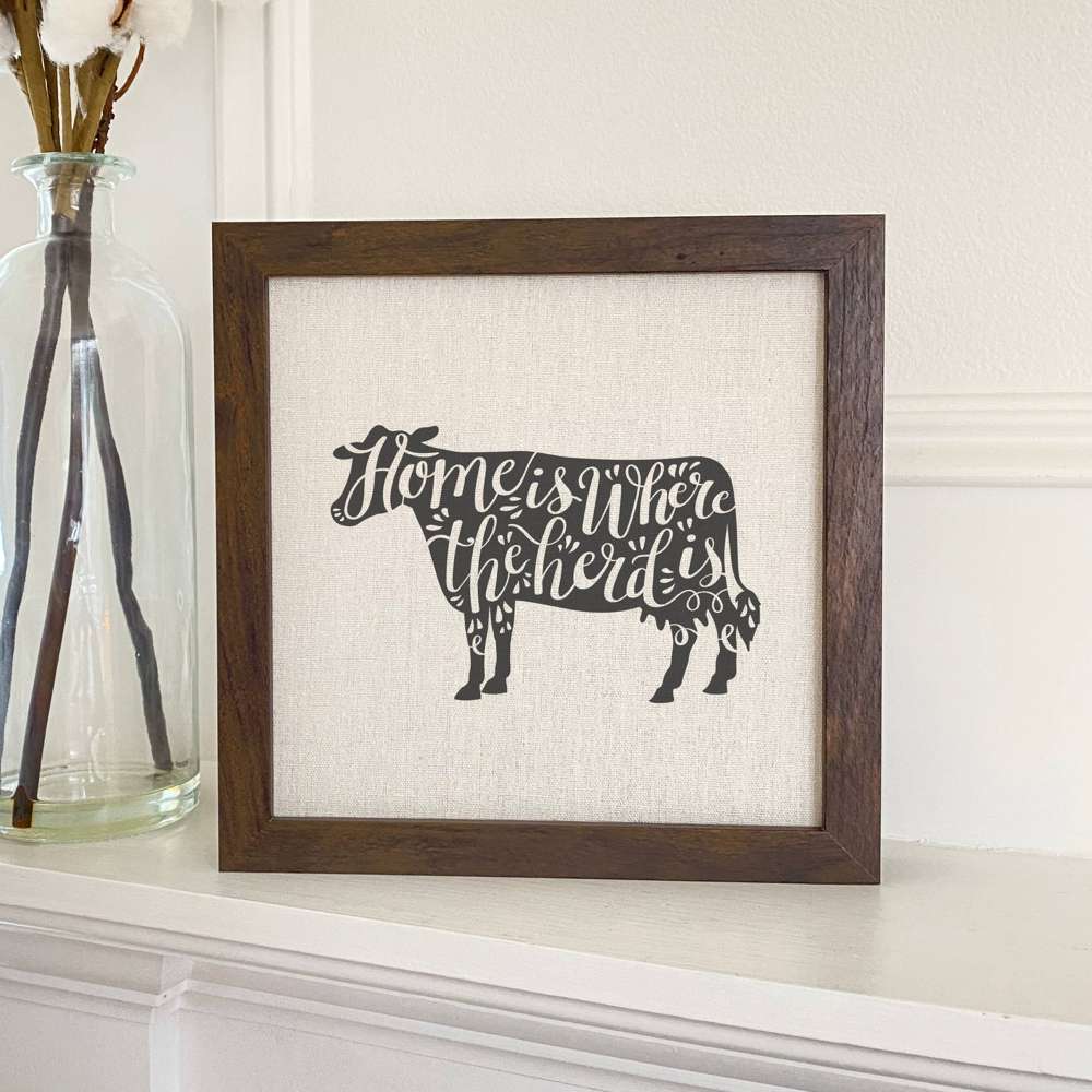 Home is Cow framed sign with a wood frame and linen-look background, perfect for home decor.