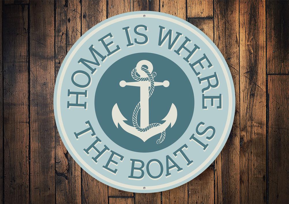 A decorative metal sign reading 'Home Is Where The Boat Is', showcasing a beautiful lakeside theme, perfect for cabin decor.