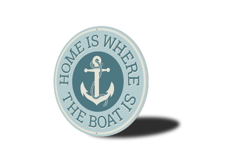 A decorative metal sign reading 'Home Is Where The Boat Is', showcasing a beautiful lakeside theme, perfect for cabin decor.