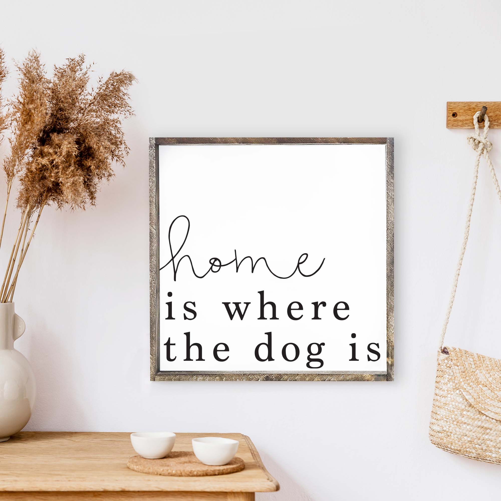 A rustic wood sign that reads 'Home Is Where The Dog Is', featuring a pine wood frame and a white background.