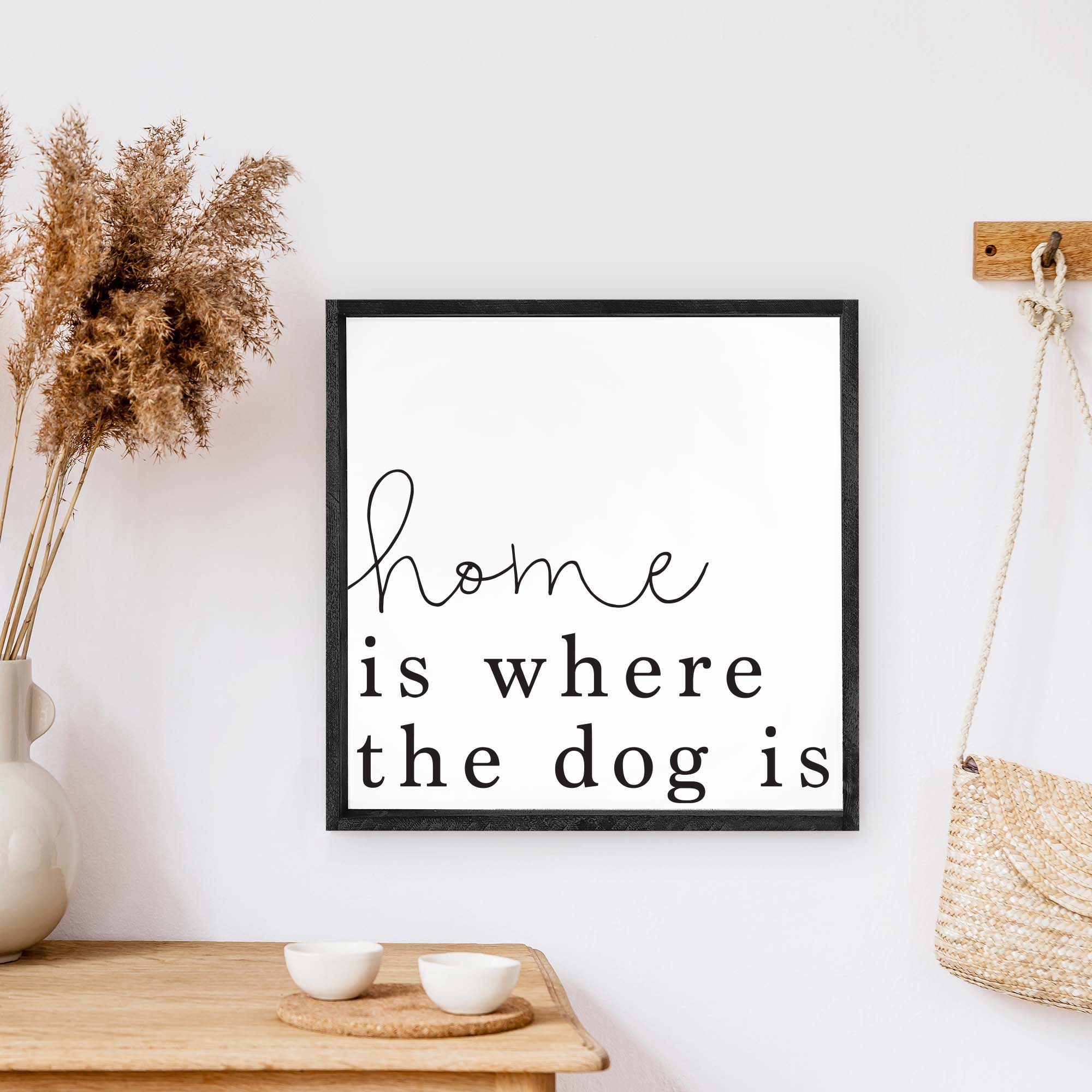 A rustic wood sign that reads 'Home Is Where The Dog Is', featuring a pine wood frame and a white background.