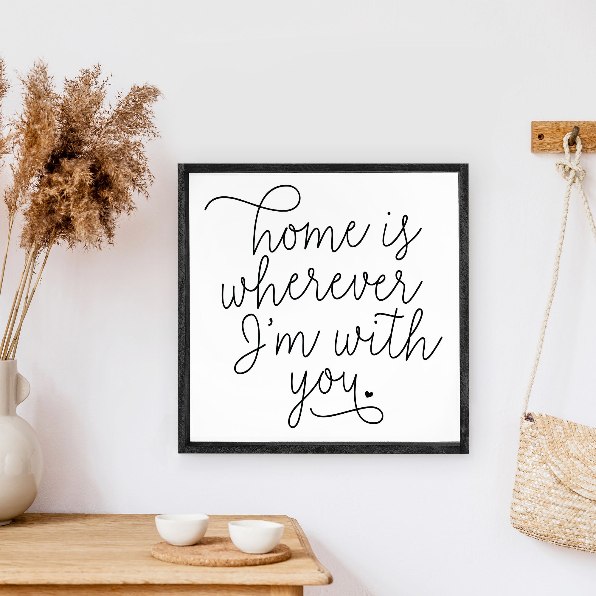 A rustic wood sign featuring the phrase 'Home Is Wherever I'm With You' in black text on a white background, framed in stained pine wood.