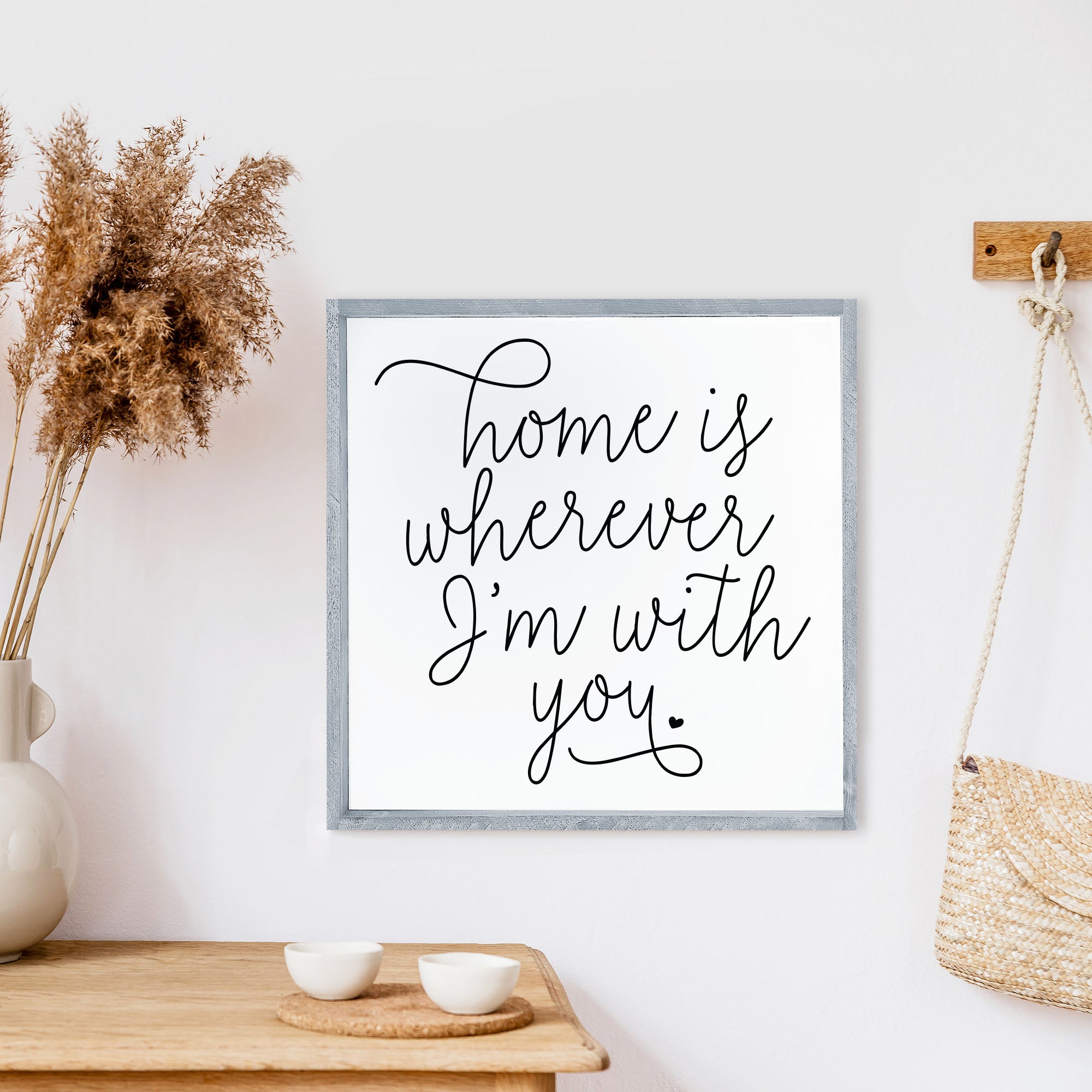 A rustic wood sign featuring the phrase 'Home Is Wherever I'm With You' in black text on a white background, framed in stained pine wood.