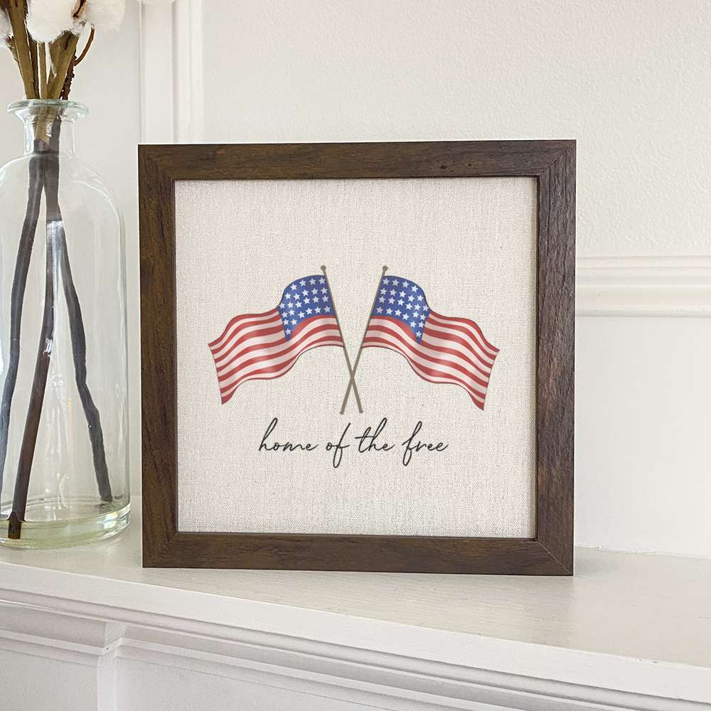 Home of the Free Flags framed sign with a natural wood frame and linen-look background, showcasing patriotic design.