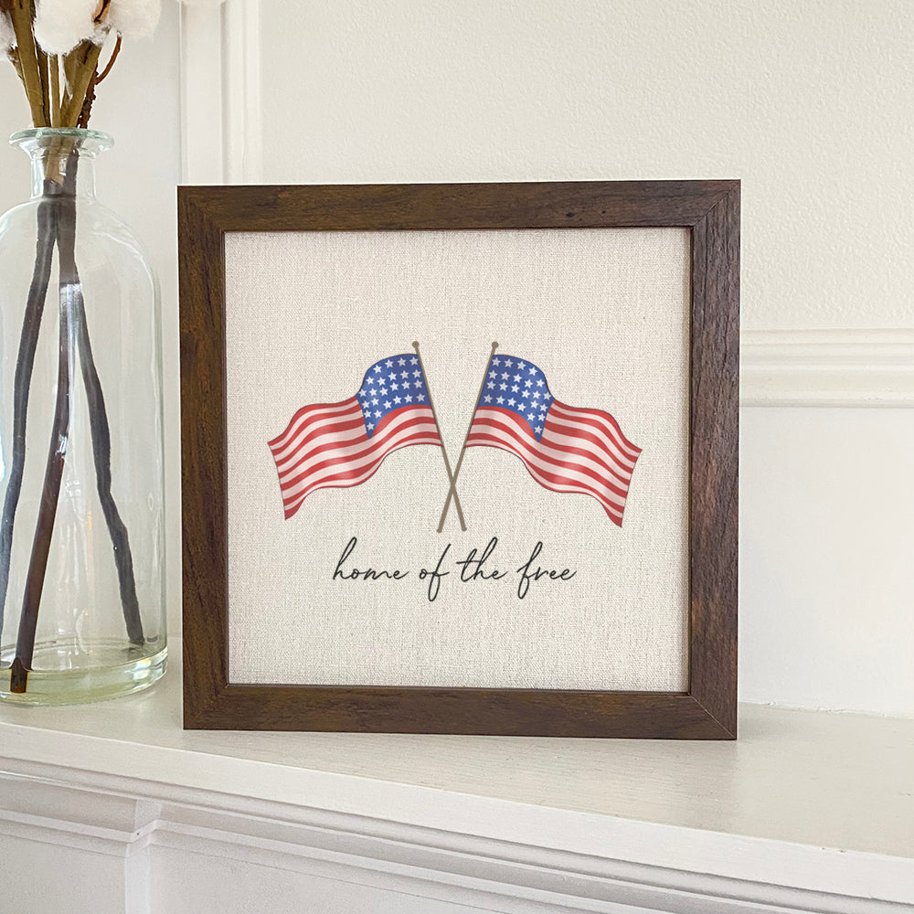 Home of the Free Flags framed sign with a natural wood frame and linen-look background, showcasing patriotic design.