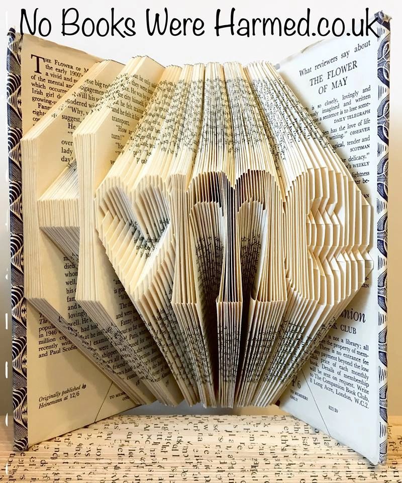 A handcrafted hollow heart art piece spelling 'Home', made from vintage book pages, showcasing intricate folds and a warm, inviting design.