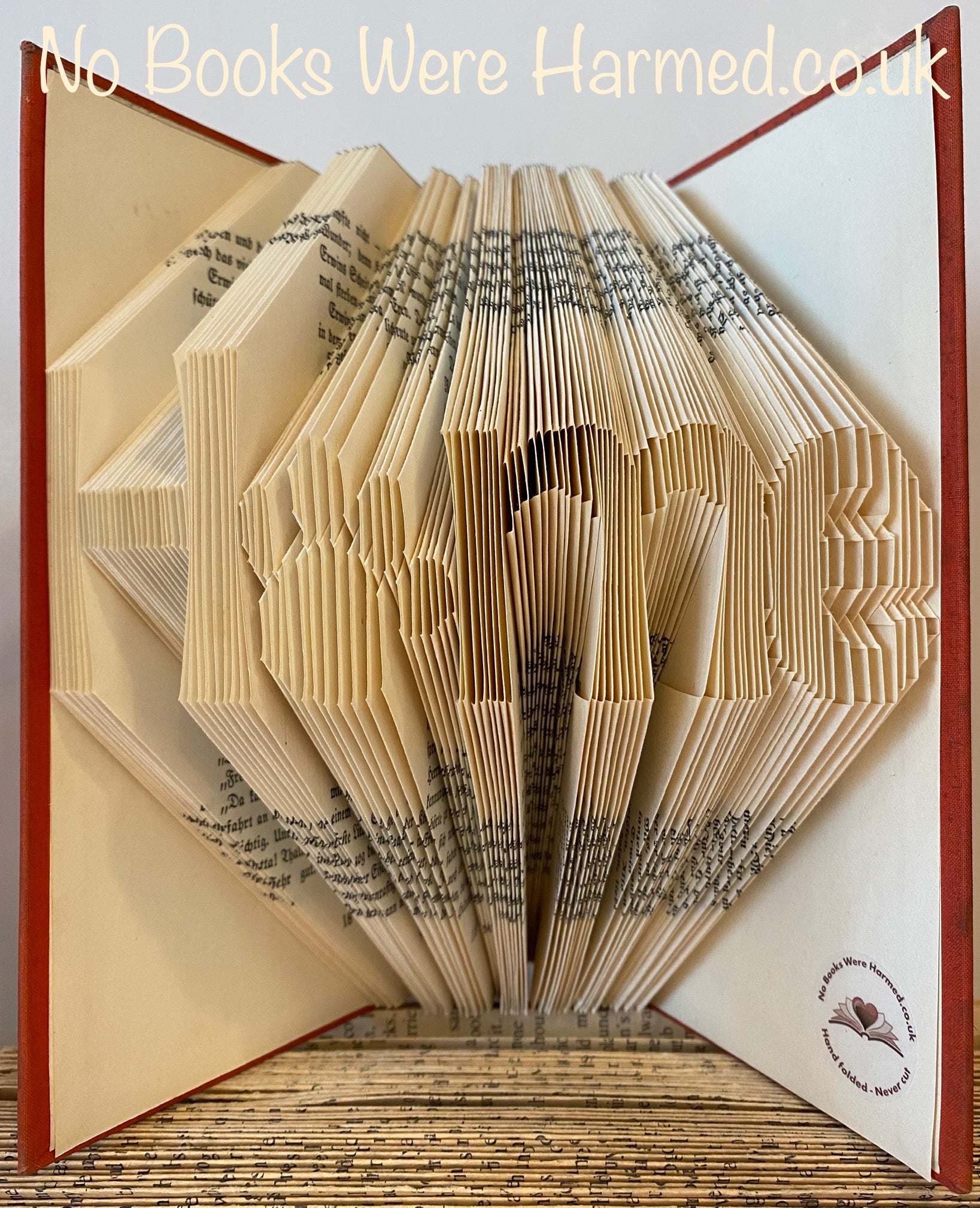 Hand-folded book art featuring the word 'Home' with a paw print as the letter 'o', showcasing unique craftsmanship.