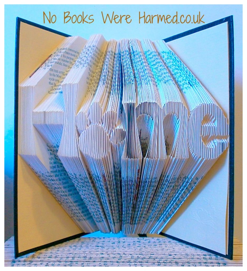 Hand-folded book art featuring the word 'Home' with a paw print as the letter 'o', showcasing unique craftsmanship.