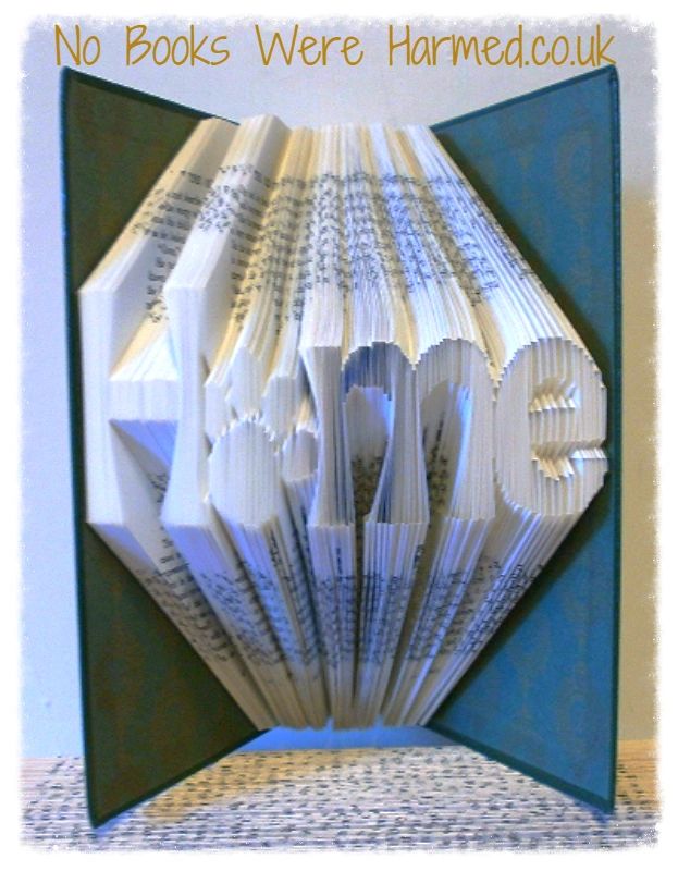 Hand-folded book art featuring the word 'Home' with a paw print as the letter 'o', showcasing unique craftsmanship.