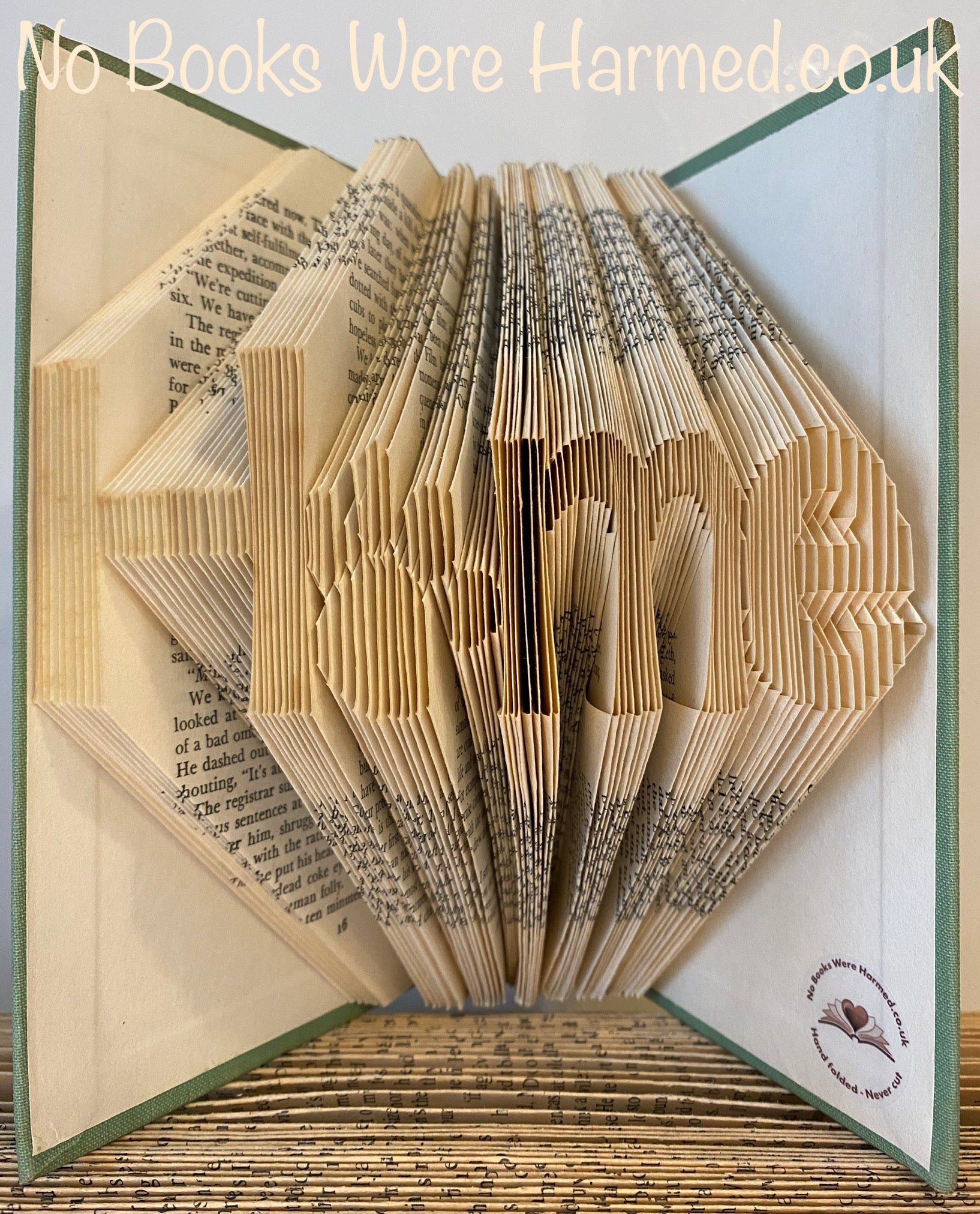 Hand-folded book art featuring the word 'Home' with a paw print as the letter 'o', showcasing unique craftsmanship.