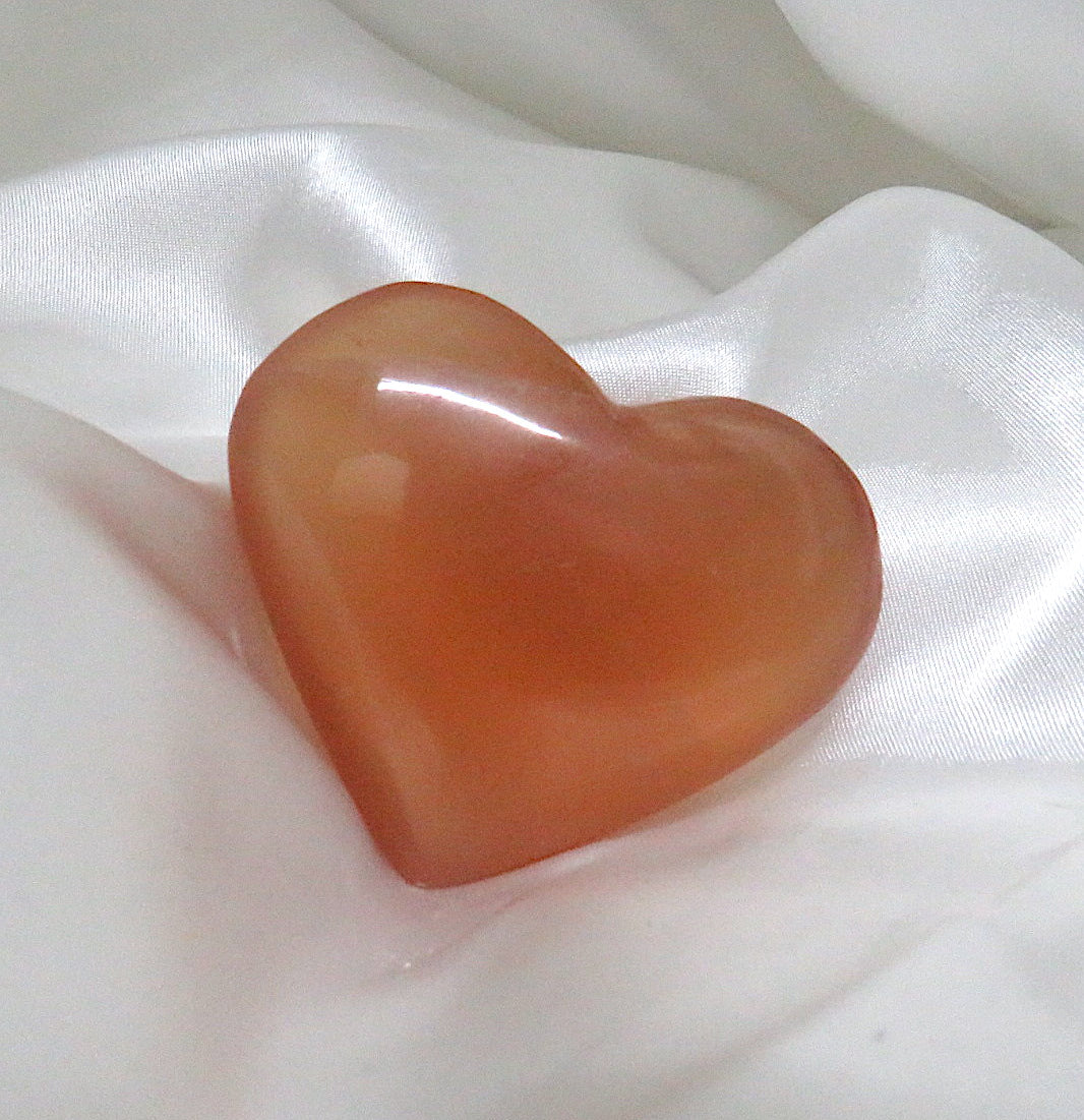 A beautifully hand-carved Honey Calcite Heart crystal showcasing its warm golden hues and unique natural imperfections.