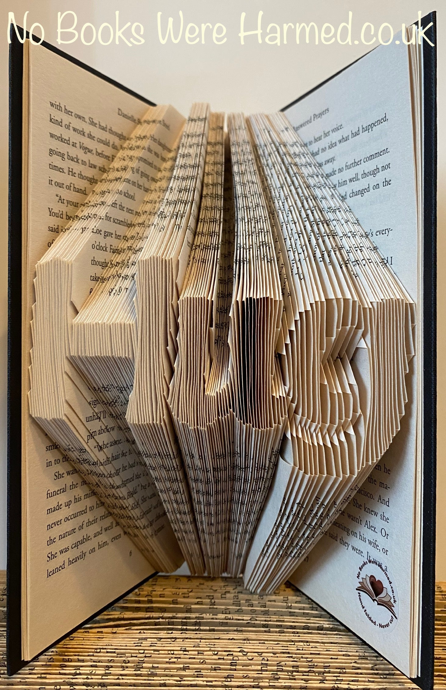 Handcrafted 'Hug' art piece made from vintage book pages, showcasing intricate folds and unique design.