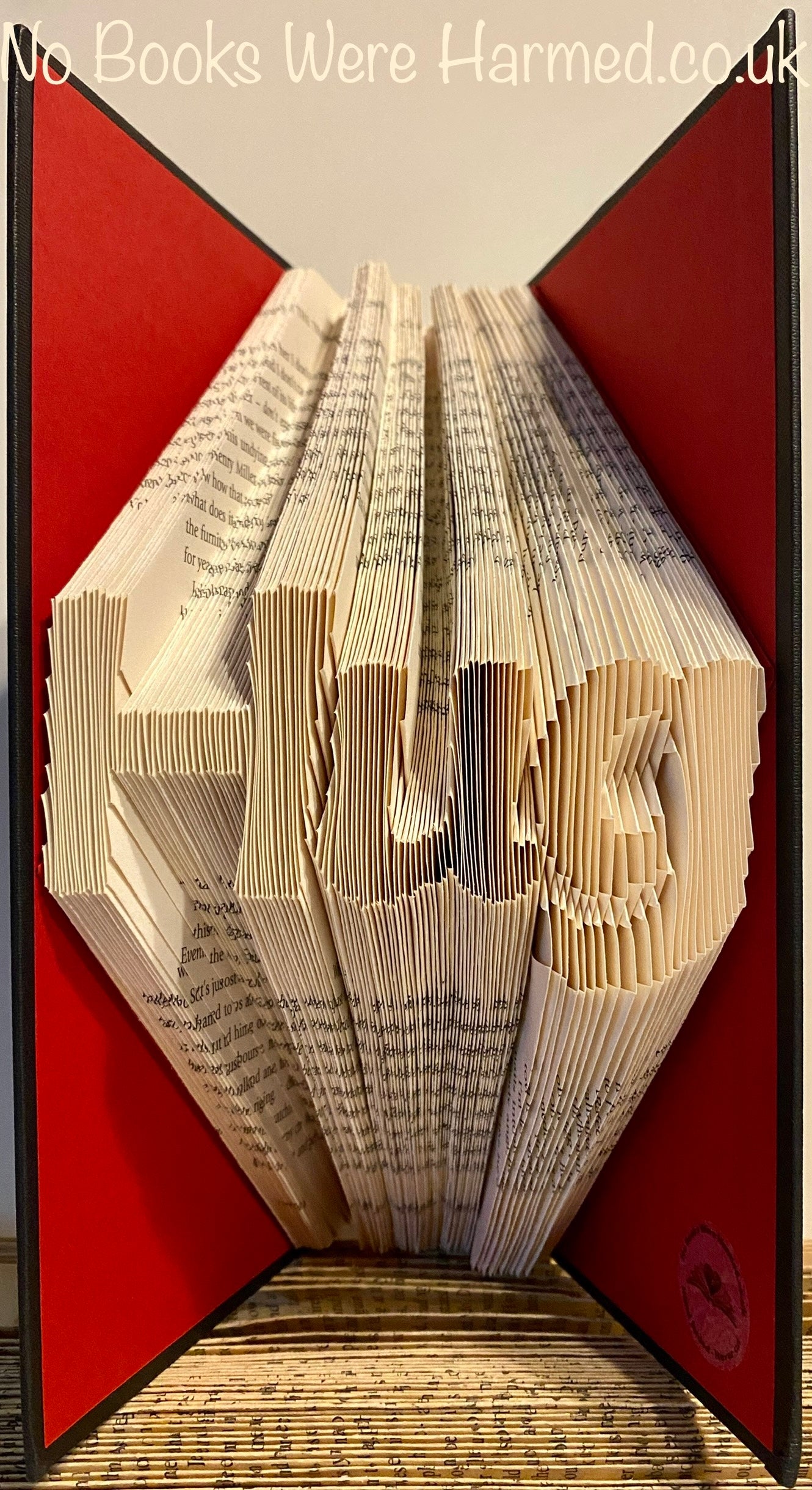 Handcrafted 'Hug' art piece made from vintage book pages, showcasing intricate folds and unique design.