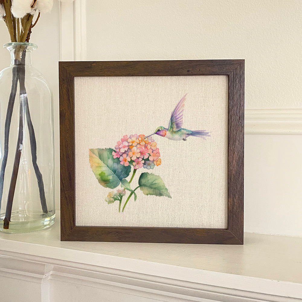 A beautifully framed sign featuring a hummingbird and lantana flowers, with a natural linen-style background and a stylish wood frame.