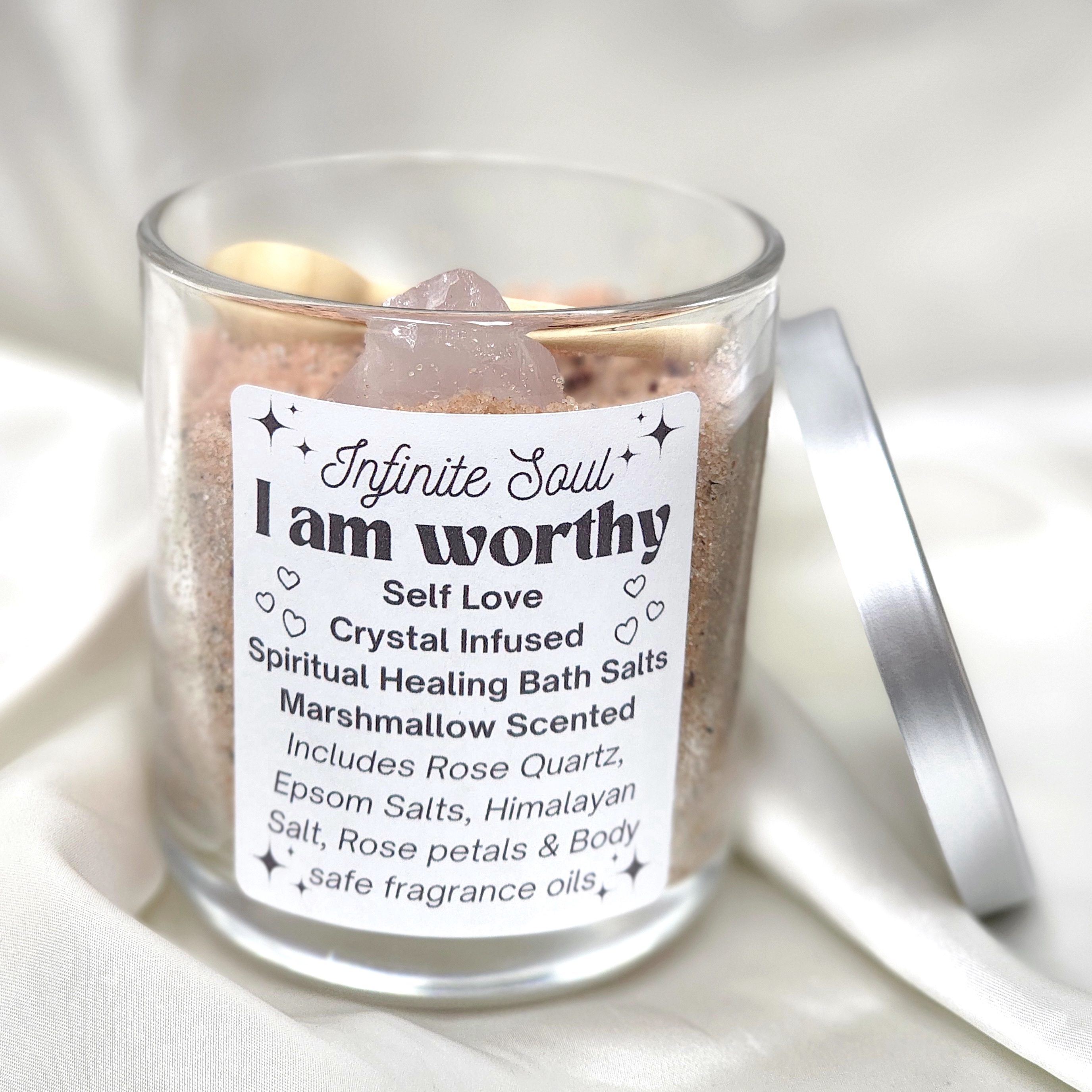 I am Worthy Self Love Crystal Infused Bath Salts in a jar with rose quartz, rose petals, and a wooden spoon, featuring a marshmallow scent.