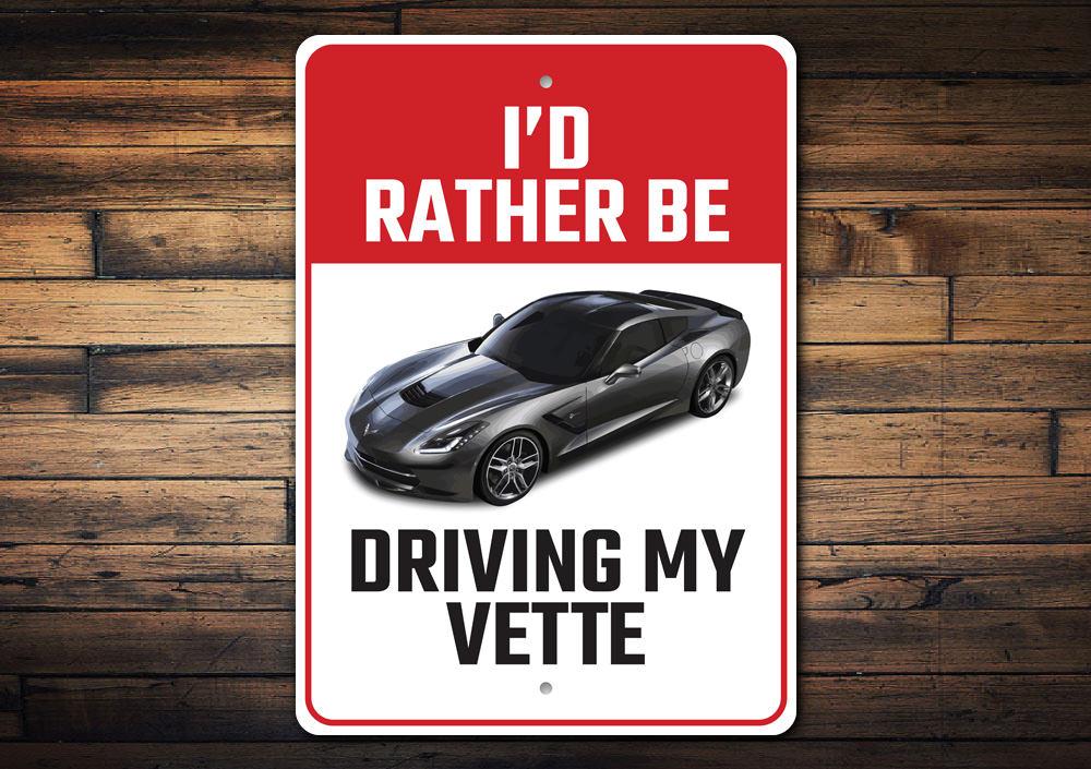 Metal sign featuring the phrase 'I'd Rather Be Driving My Corvette', showcasing a sleek design perfect for car enthusiasts.