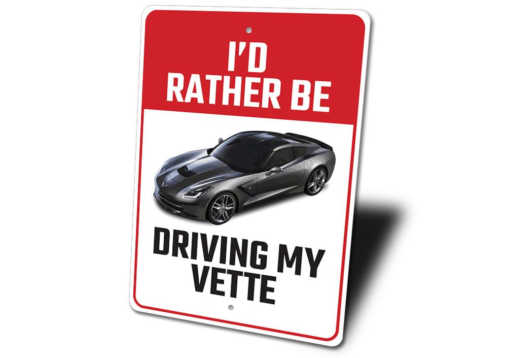 Metal sign featuring the phrase 'I'd Rather Be Driving My Corvette', showcasing a sleek design perfect for car enthusiasts.