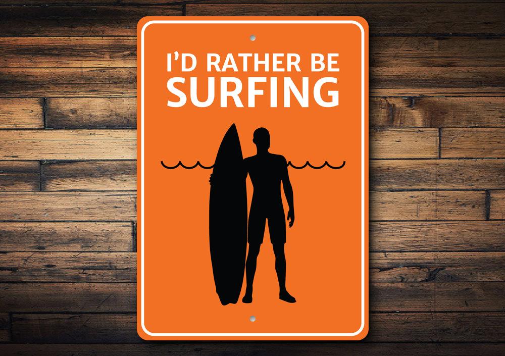 A decorative metal sign reading 'I'd Rather Be Surfing', featuring vibrant colors and a beach-themed design, perfect for coastal decor.