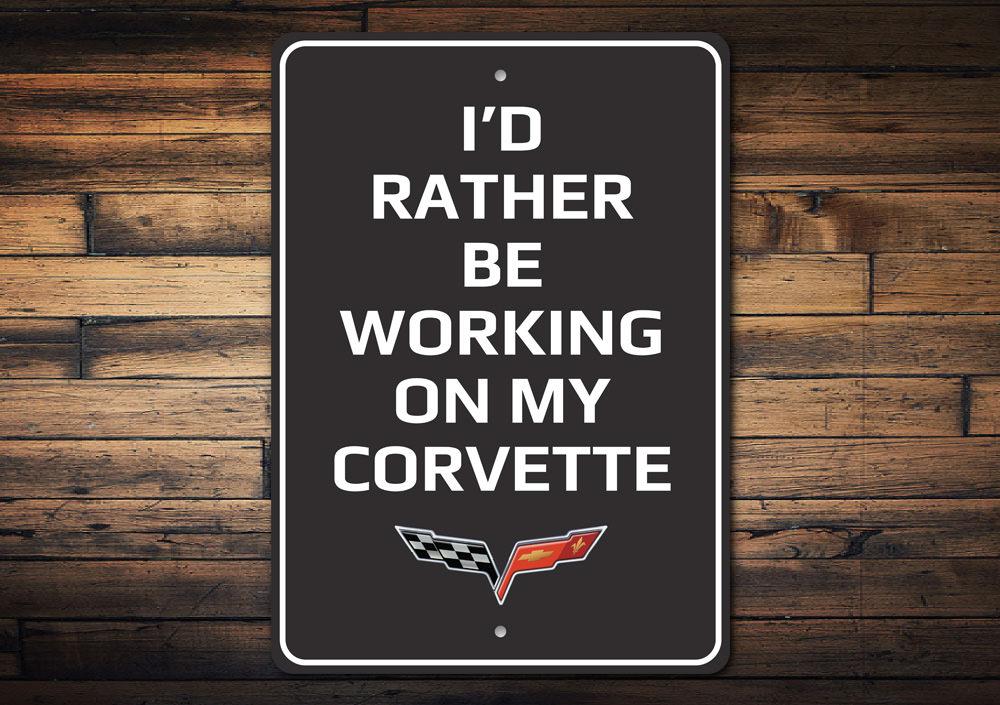 Metal sign featuring the phrase 'I'd Rather Be Working On My Corvette', showcasing a sleek design suitable for car enthusiasts.