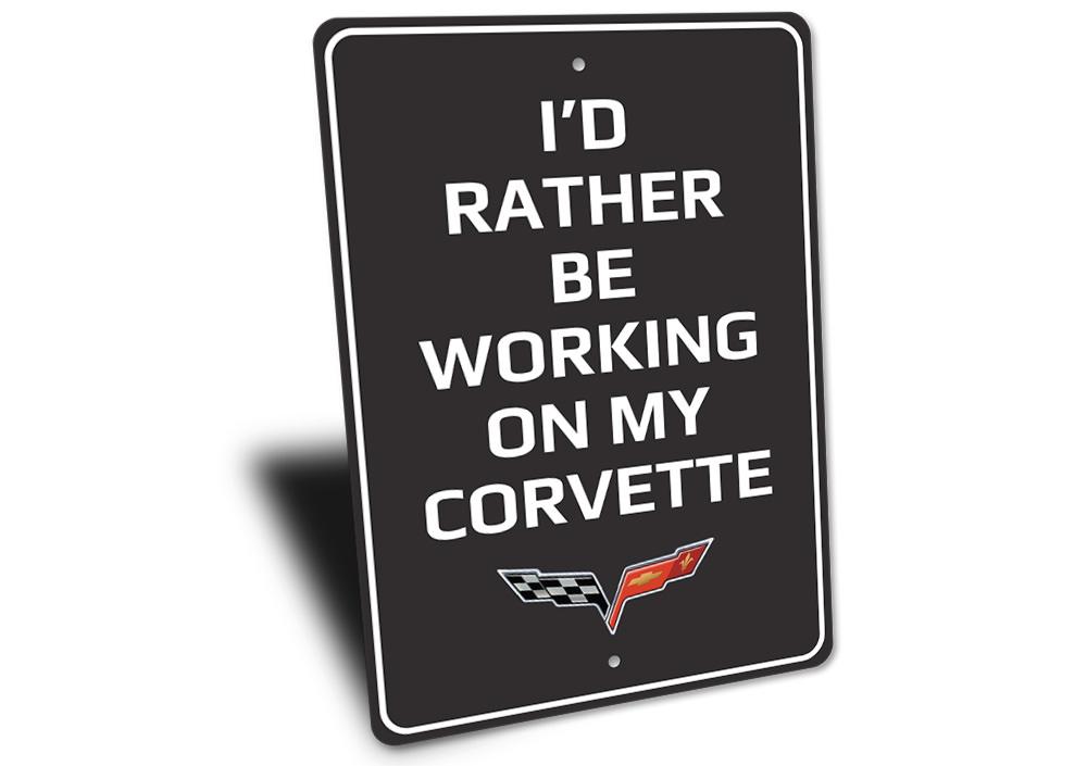 Metal sign featuring the phrase 'I'd Rather Be Working On My Corvette', showcasing a sleek design suitable for car enthusiasts.