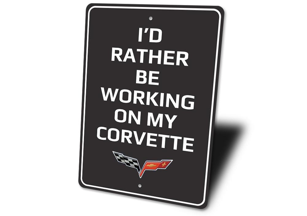 Metal sign featuring the phrase 'I'd Rather Be Working On My Corvette', showcasing a sleek design suitable for car enthusiasts.