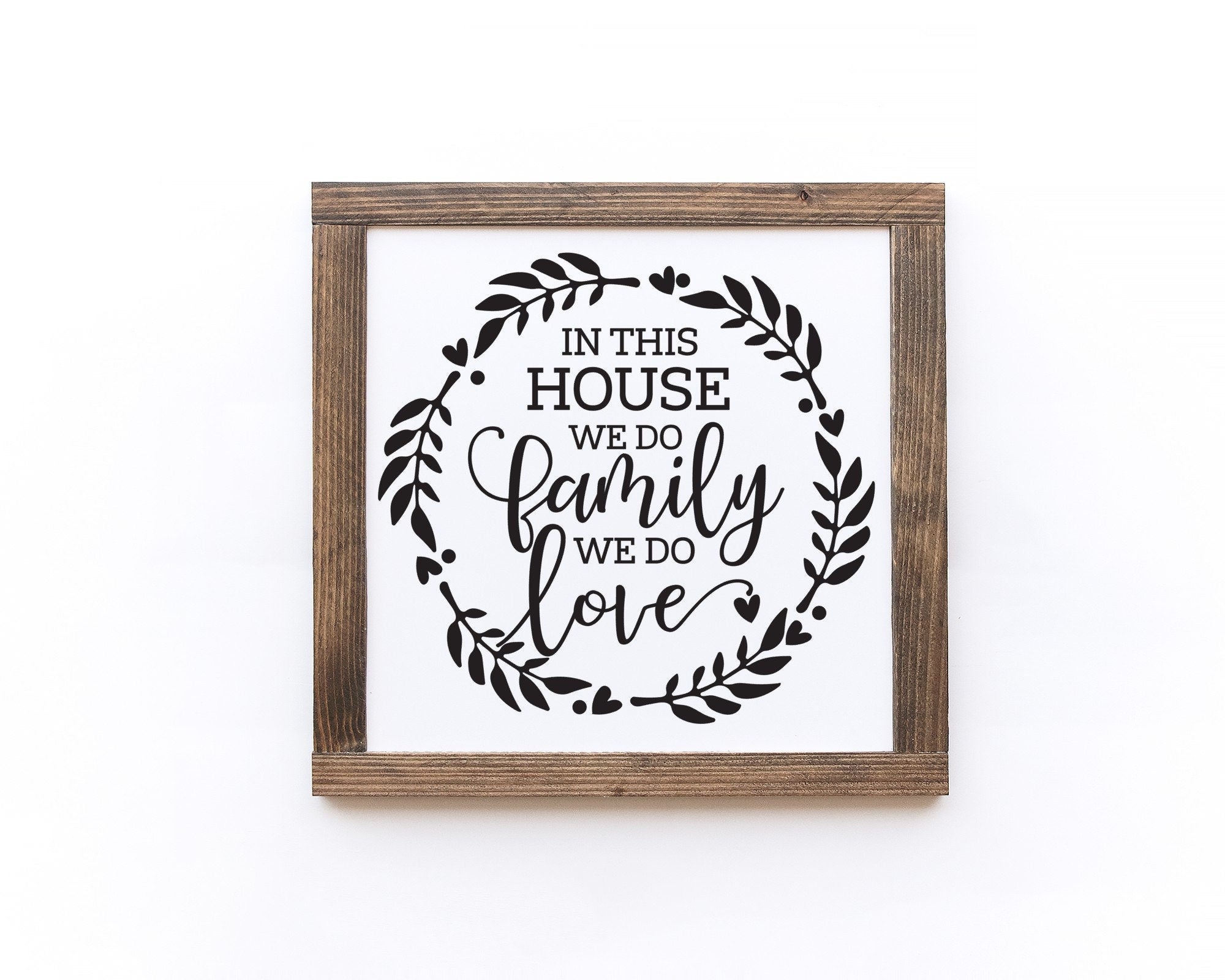 Handmade wood sign with the phrase 'In This House We Do Family We Do Love', featuring a matte white background and unique wood grain.