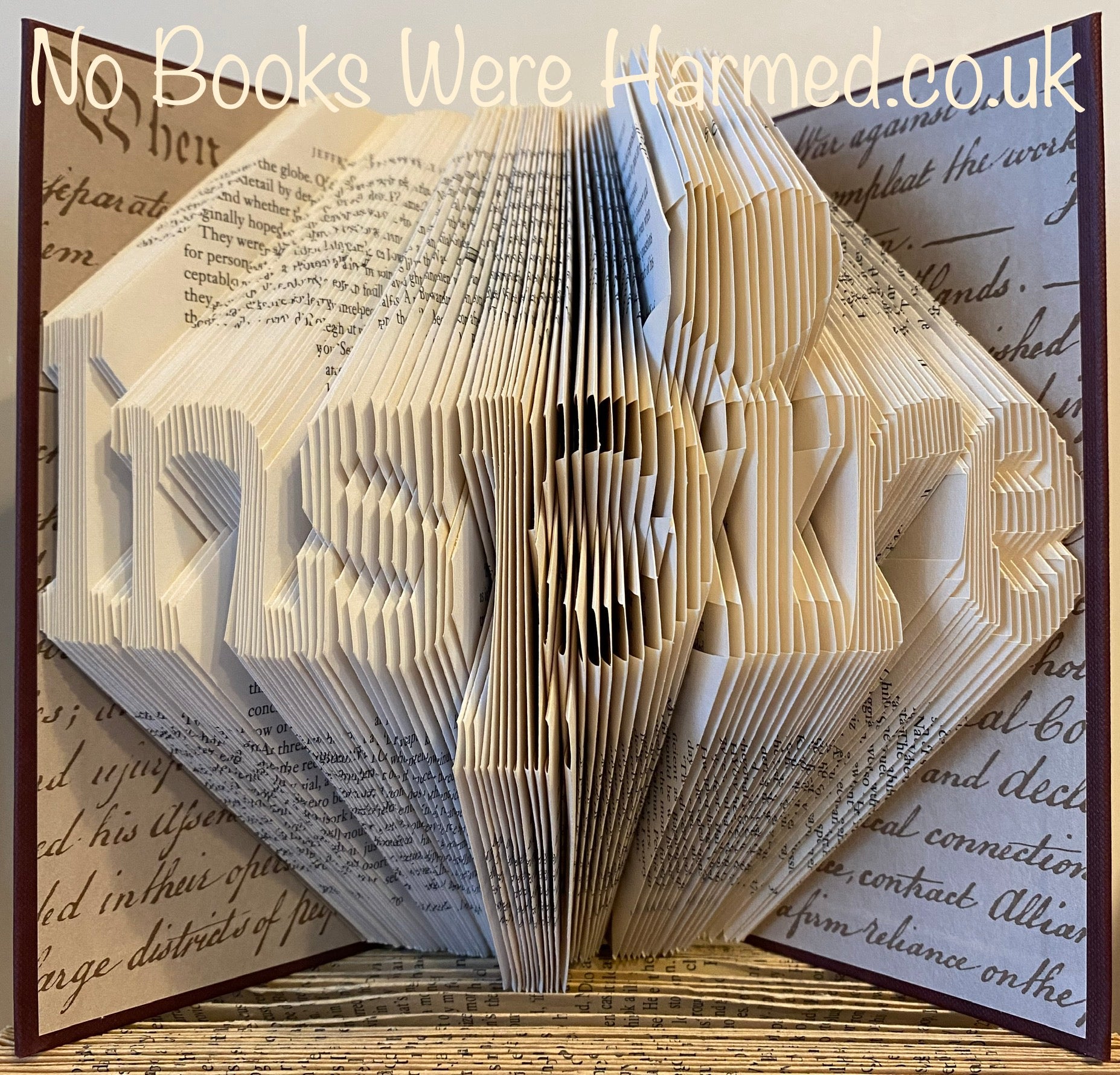 Hand-folded book art titled 'Inspire', showcasing intricate designs made from vintage books.