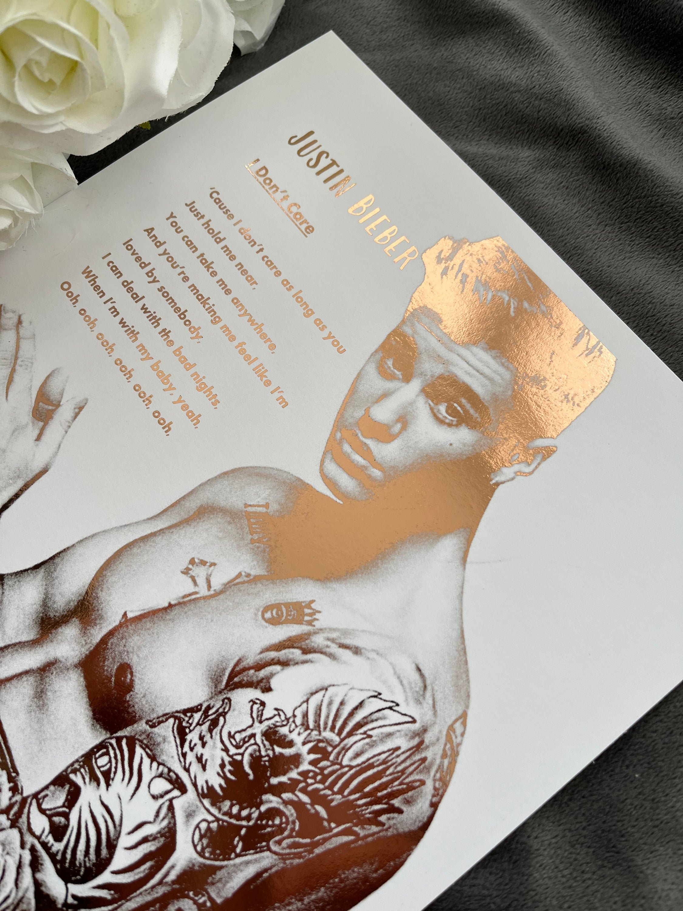 A stunning foil print of Justin Bieber featuring a rose gold portrait and song lyrics on a white background.