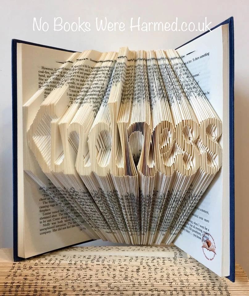 A unique piece of book art titled Kindness, handcrafted from vintage books with intricate hand-folded pages.