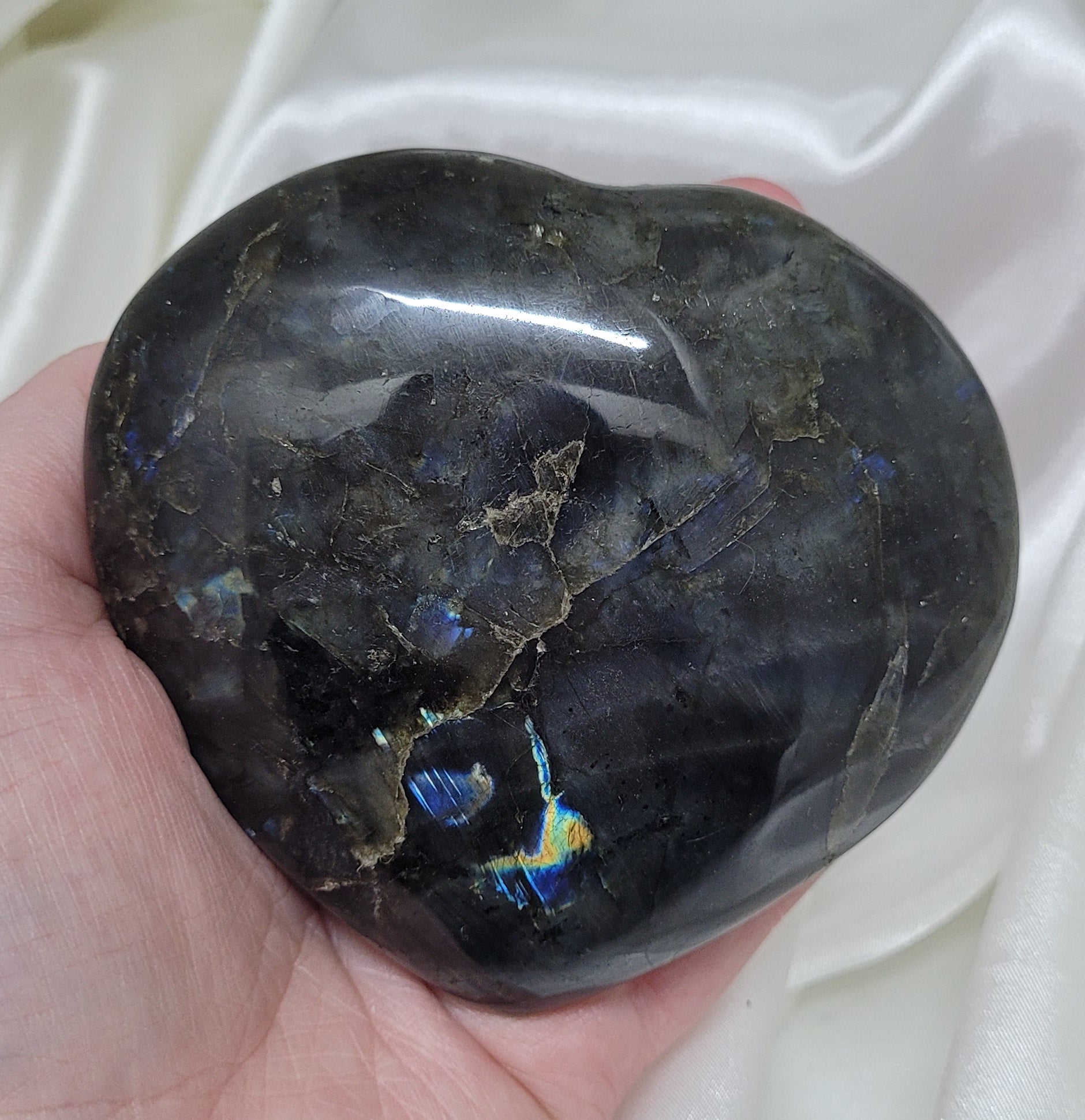 A beautifully hand-carved labradorite heart showcasing its unique colors and textures, symbolizing protection and intuition.