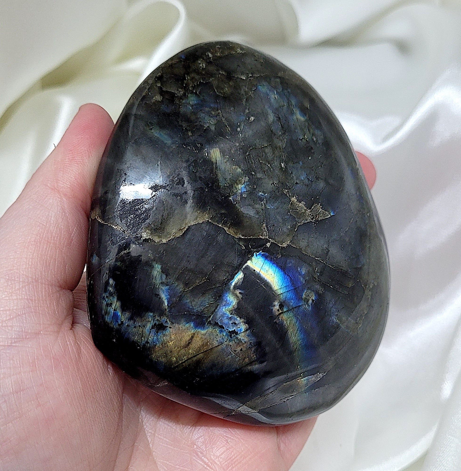 A beautifully hand-carved labradorite heart showcasing its unique colors and textures, symbolizing protection and intuition.