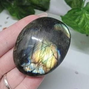 A beautifully hand-carved Labradorite Palm Stone showcasing its unique iridescent colors and smooth surface, perfect for meditation and healing.