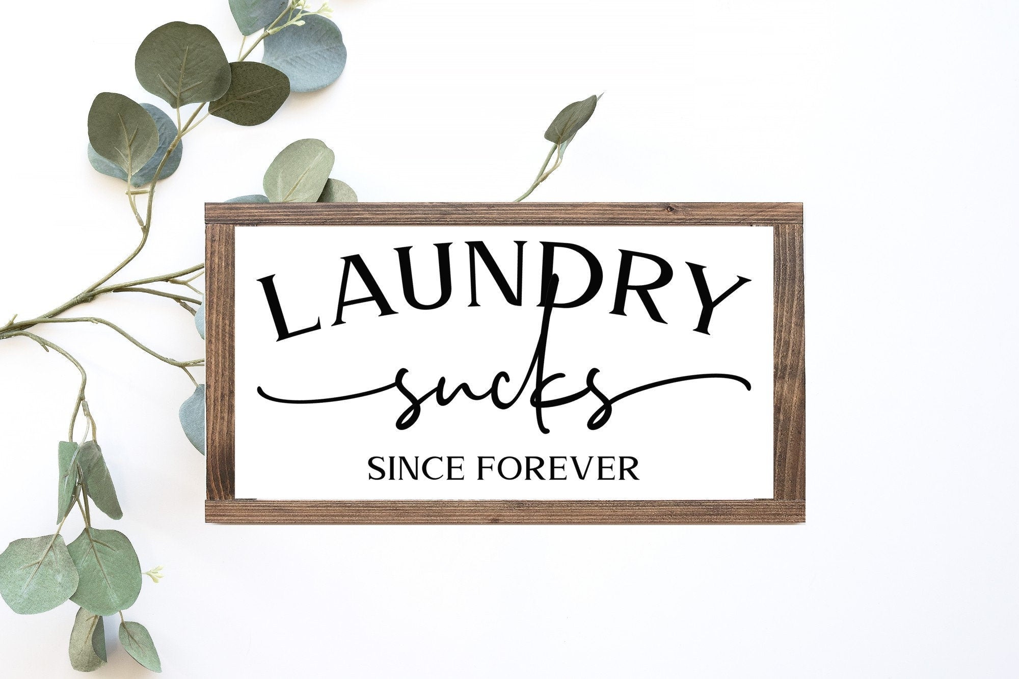 Laundry Sucks Since Forever Wood Sign in matte white finish, showcasing humorous lettering on a rustic wooden background.