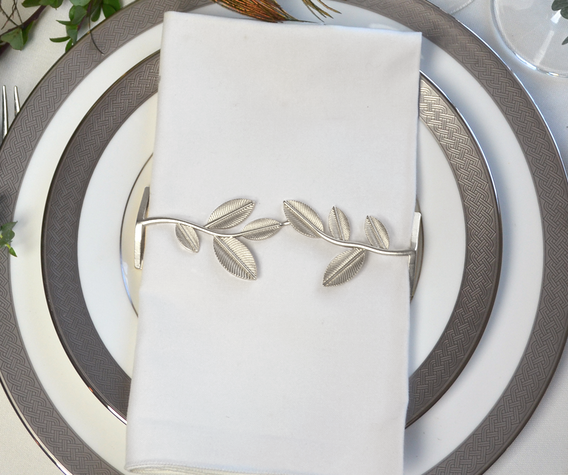 A set of four elegant silver leaf napkin wraps displayed in a stylish box, perfect for enhancing dining experiences.