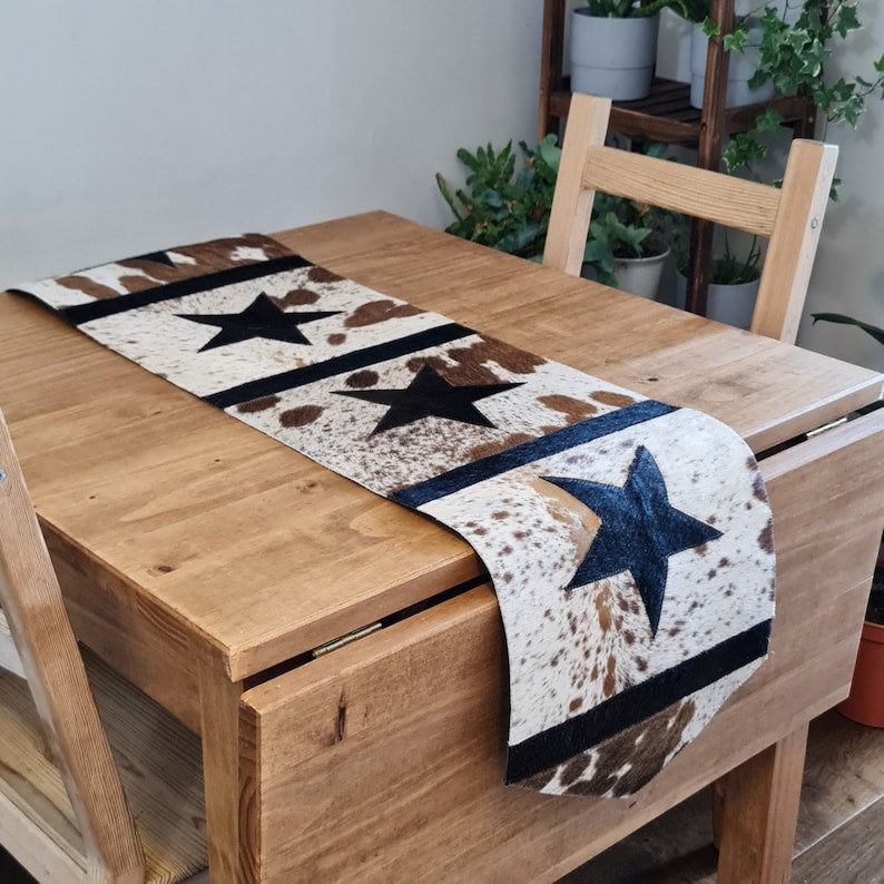 A stylish 16" x 96" leather cow skin table runner featuring a unique star pattern, showcasing its rich texture and color variations.