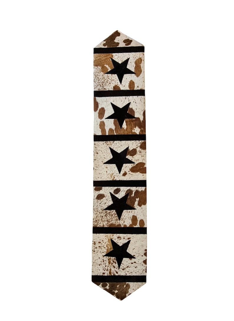 A stylish 16" x 96" leather cow skin table runner featuring a unique star pattern, showcasing its rich texture and color variations.