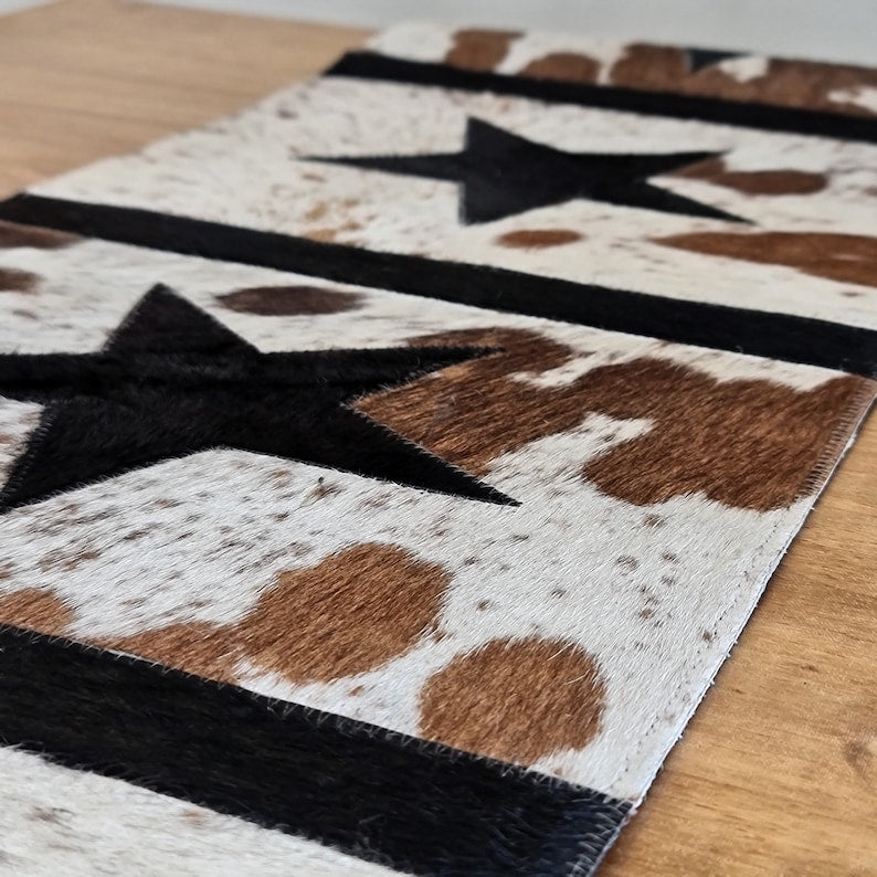 A stylish 16" x 96" leather cow skin table runner featuring a unique star pattern, showcasing its rich texture and color variations.