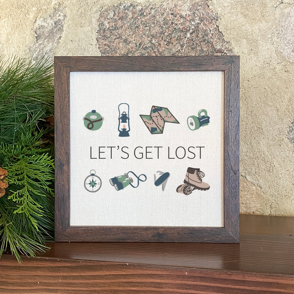 A beautifully framed sign that reads 'Let's Get Lost', featuring a natural wood frame and a linen-look neutral background.