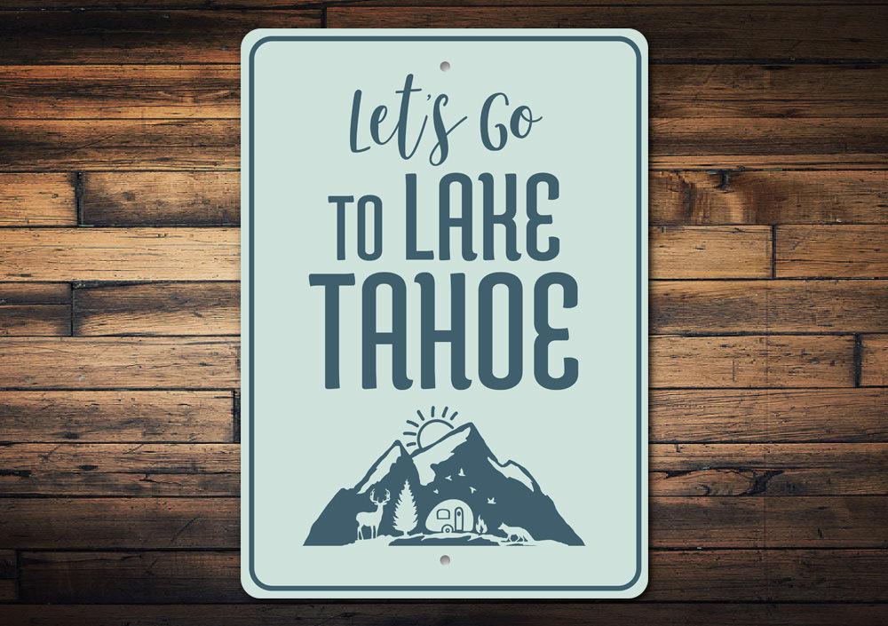 A decorative metal sign featuring 'Let's Go to Lake Tahoe' text, showcasing a beautiful lake scene, perfect for lakehouse decor.