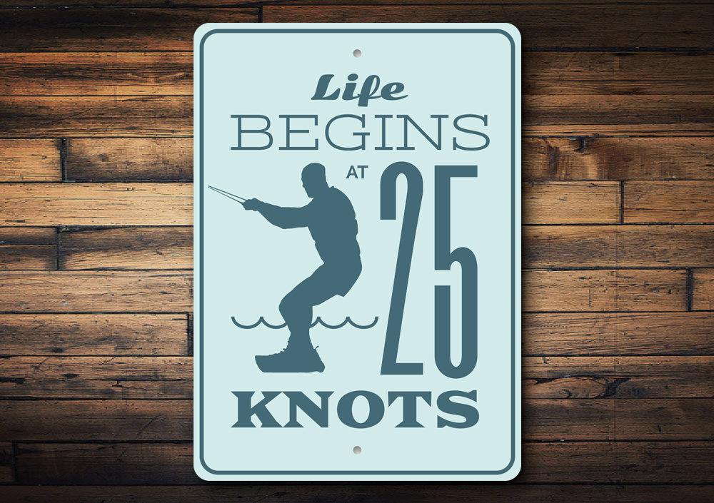 Life Begins at 25 Knots decorative sign made of aluminum, featuring a coastal theme, perfect for beach houses and outdoor decor.